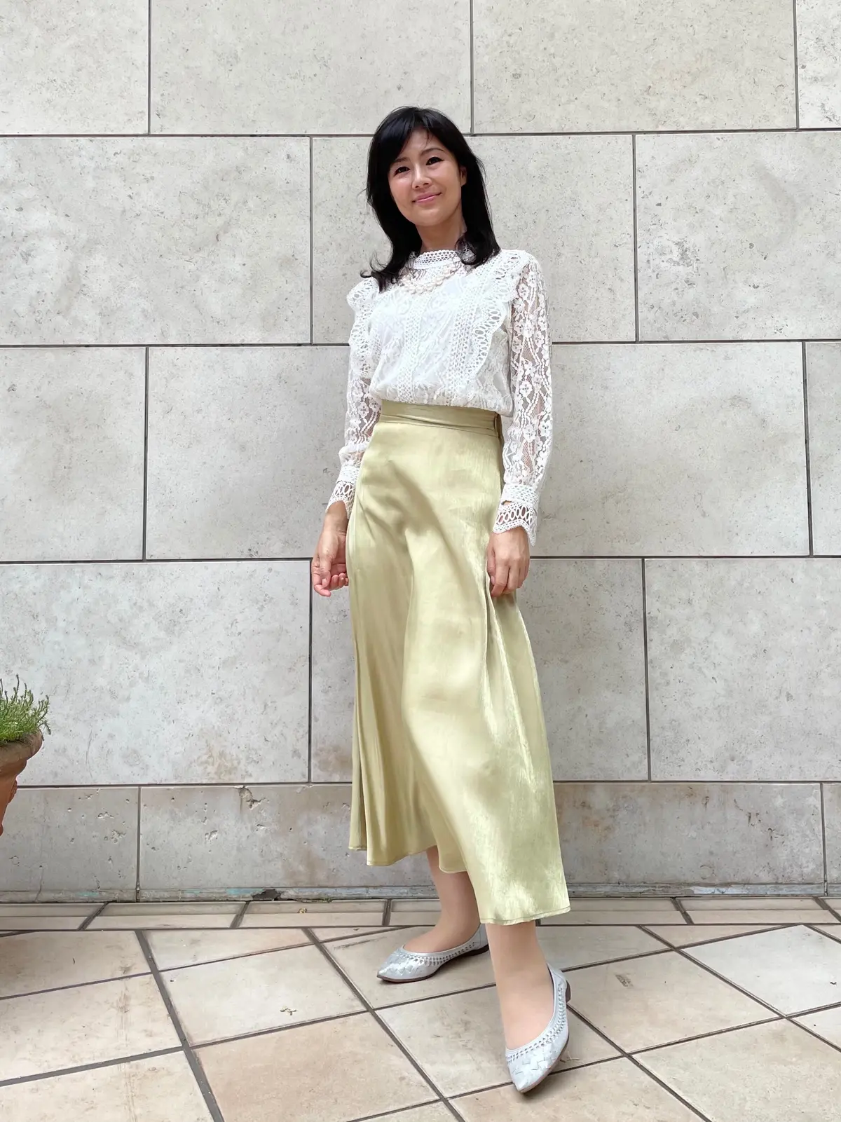 白いレースのトップスに薄手の黄緑色のロングスカートのコーデ。