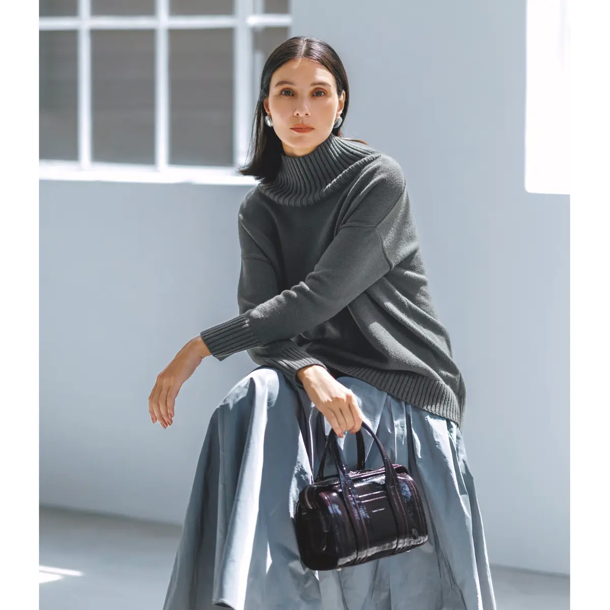 ミディアムグレーのボトルネックニットにライトグレーのフレアースカートを合わせたコーディネート　モデル・田沢美亜　