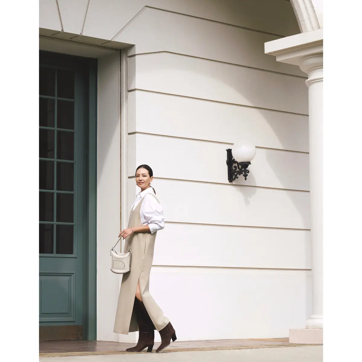 白シャツにベージュノースリーブワンピースを重ねて、ブラウンロングブーツを合わせたコーディネート　モデル・RINA