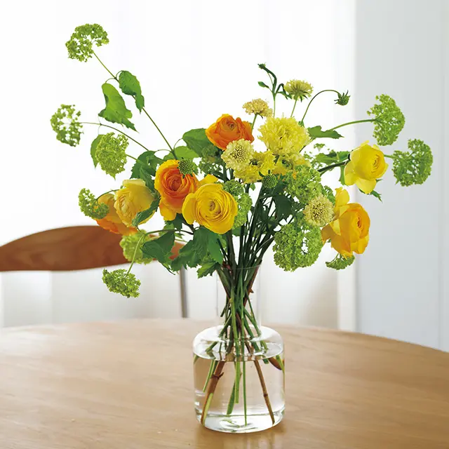 ラナンキュラスにビバーナム スノーボールを合わせ、首がすっと伸びたカラフェからあふれ出すイメージでたっぷりと。