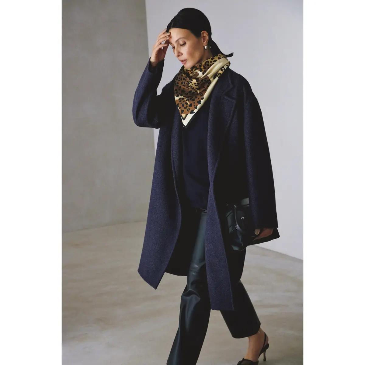 ネイビーのコートとニットを合わせてレオパード柄スカーフを首元に巻き、黒レザーパンツを合わせたコーディネート　モデル・田沢美亜