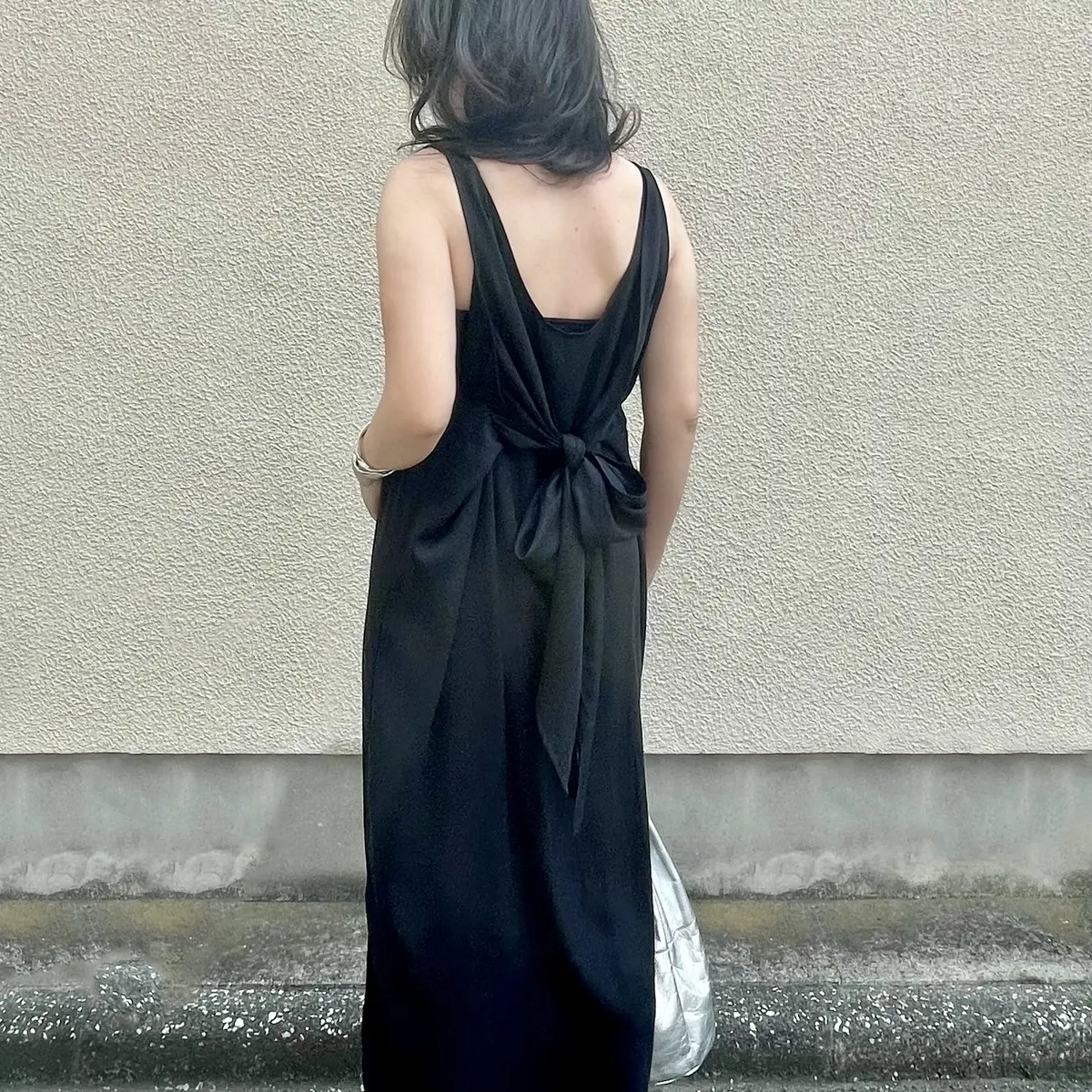 黒ワンピース（バックスタイル）、シルバーバッグ