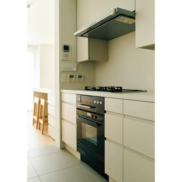 リビング側から見えない部分の収納扉はメラミン材に。扉やレールを付け替え、ユニットはリノベーション前のものを再利用。ガスコンロ、オーブンはリンナイ。換気扇は富士工業。換気扇の両側の開き戸内にはワイングラスなどを収納している