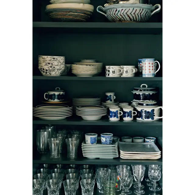 パントリーも兼ね、ダイニングの梁下の壁面を全面収納にした。開き戸なので奥行きは浅めに。Fさんが退職する際に記念に購入したブラックパラティッシシリーズや、お母さまから譲り受けたアラビアの食器、グラス類などが整然と並ぶ　