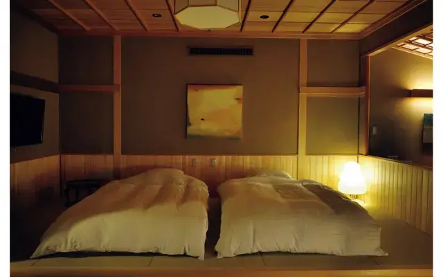 寝室はモダンなローベッド。館内には現代アートがさりげなく飾られており、老舗の風格とモダンさのバランスが絶妙