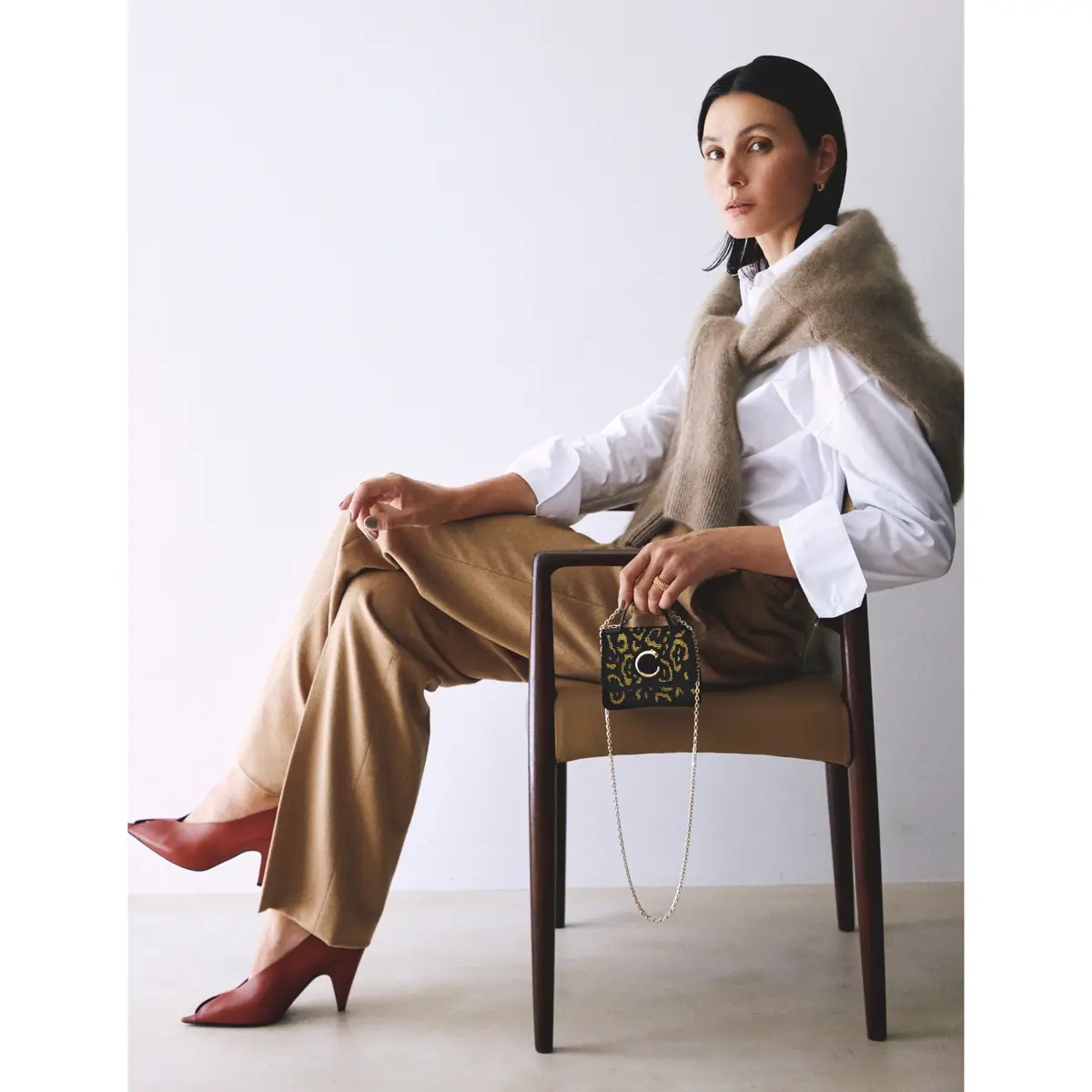 白シャツの上にベージュニットを肩がけし、キャメルパンツを合わせたコーディネート　モデル・田沢美亜