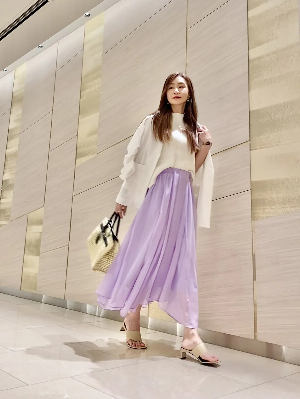 ラベンダーカラーのスカートにホワイトのジャケットを羽織って