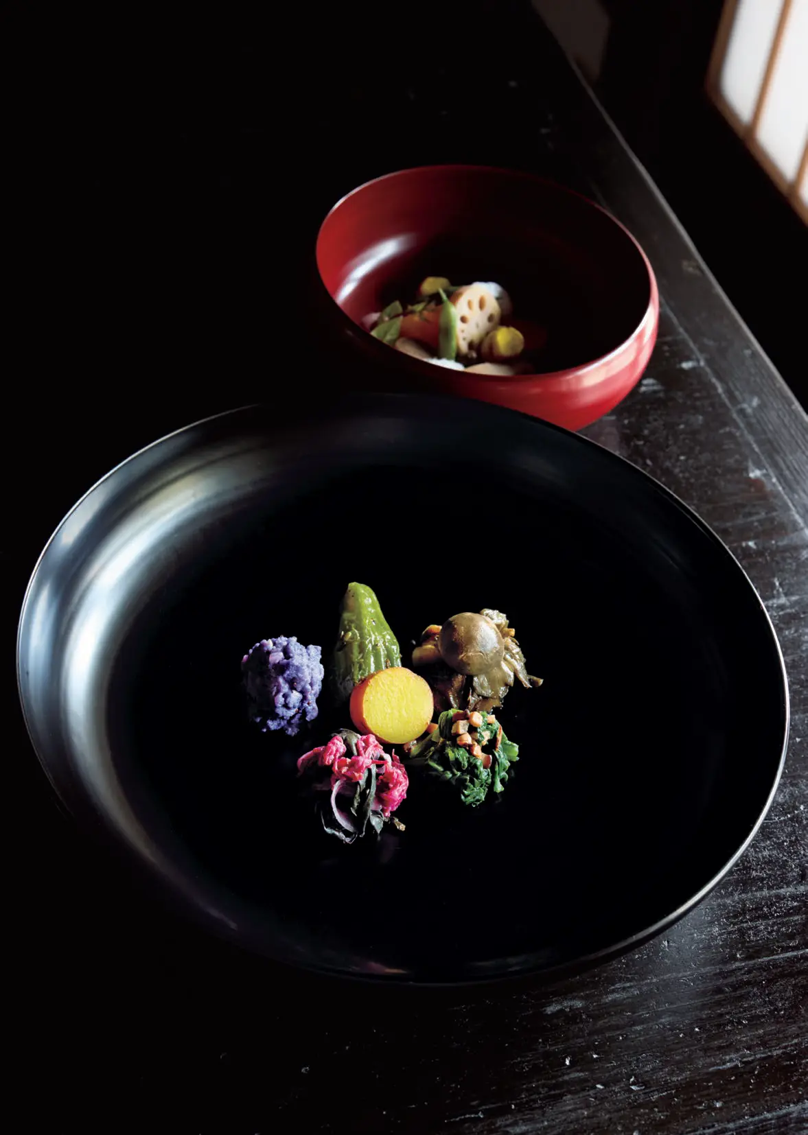 海辺の食堂 杣径　料理の写真　手前はみかん果汁で炊いた甘藷、 金時草ほか赤い野菜の酢の物など野菜料理盛り 合わせ「虚空」。奥は神子原れんこん、沢野ご ぼうなど能登在来種の根菜類吹き寄せ「能登鉢」。 ランチはごはんと味噌汁つきで￥2,000、＋魚 料理と甘味￥5,500。ディナーは￥19,800