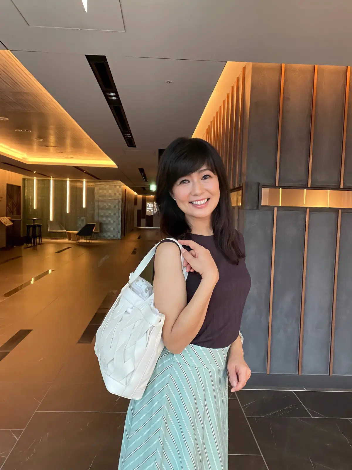 白いバッグ。こげ茶のノースリーブにペパーミントグリーンのストライプのロングカート。