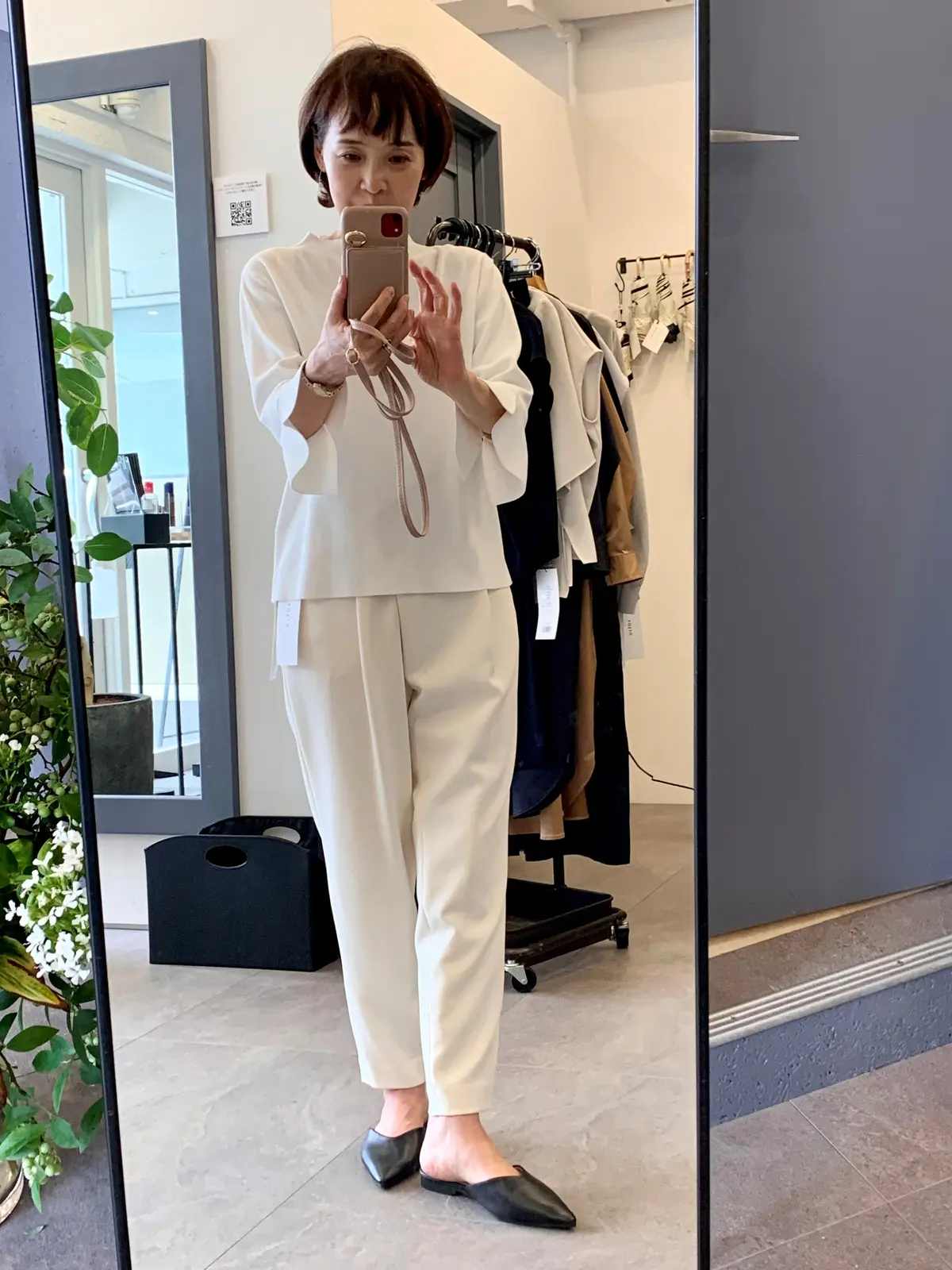 白のトップスとパンツを試着する女性