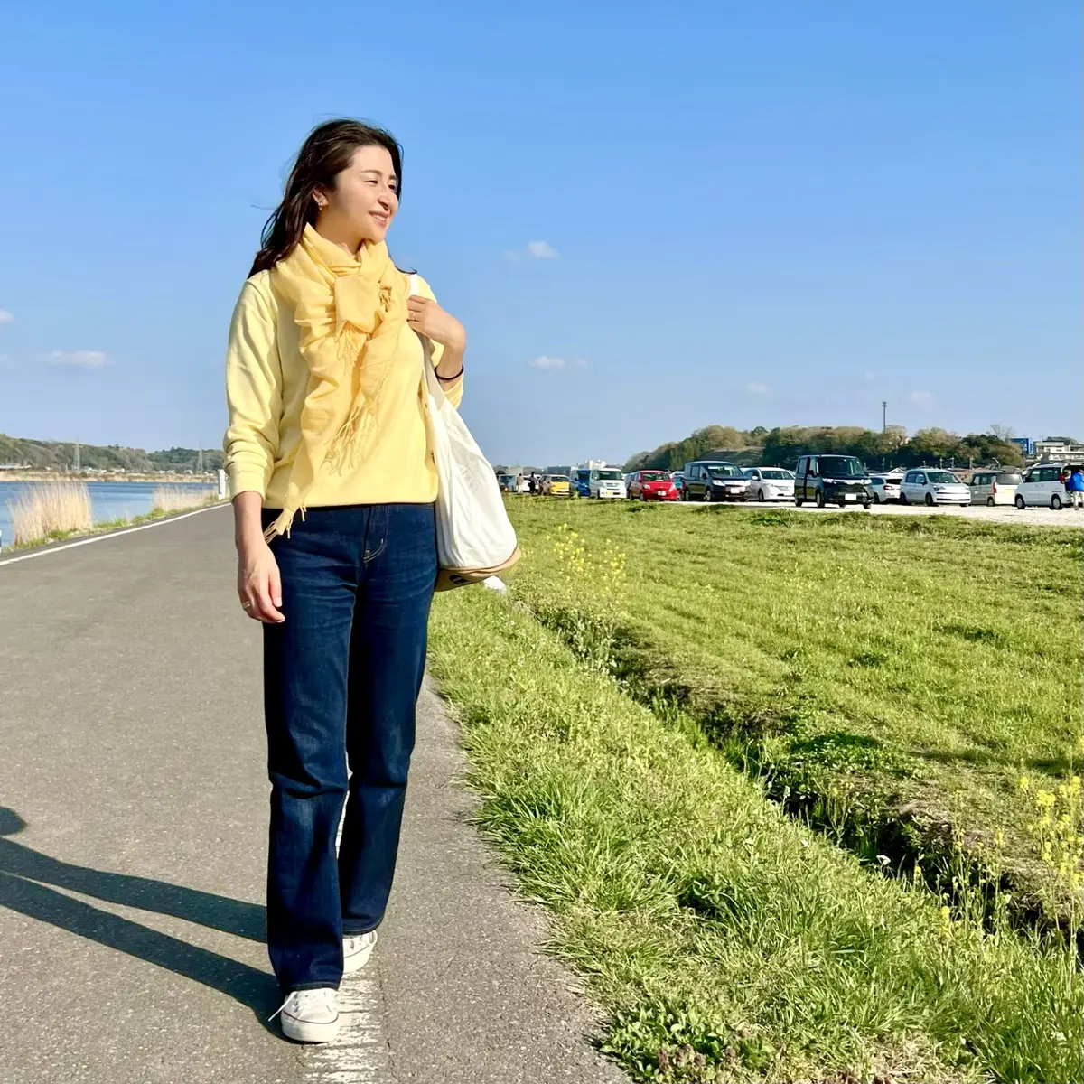 UNIQLOのイエローニット、フレアーデニム、白のスニーカー、白のバッグ、イエローのストール