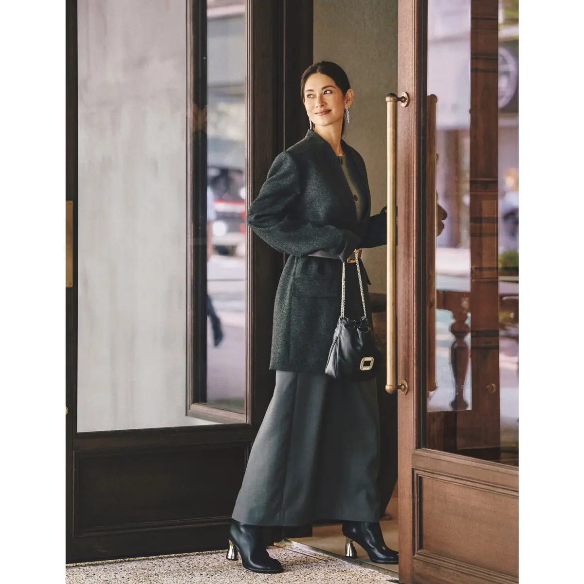 ダークグレーのノーカラージャケットコートの上からレザーベルトを締め、グレーロングスカートを合わせたコーディネート　モデル・ブレンダ