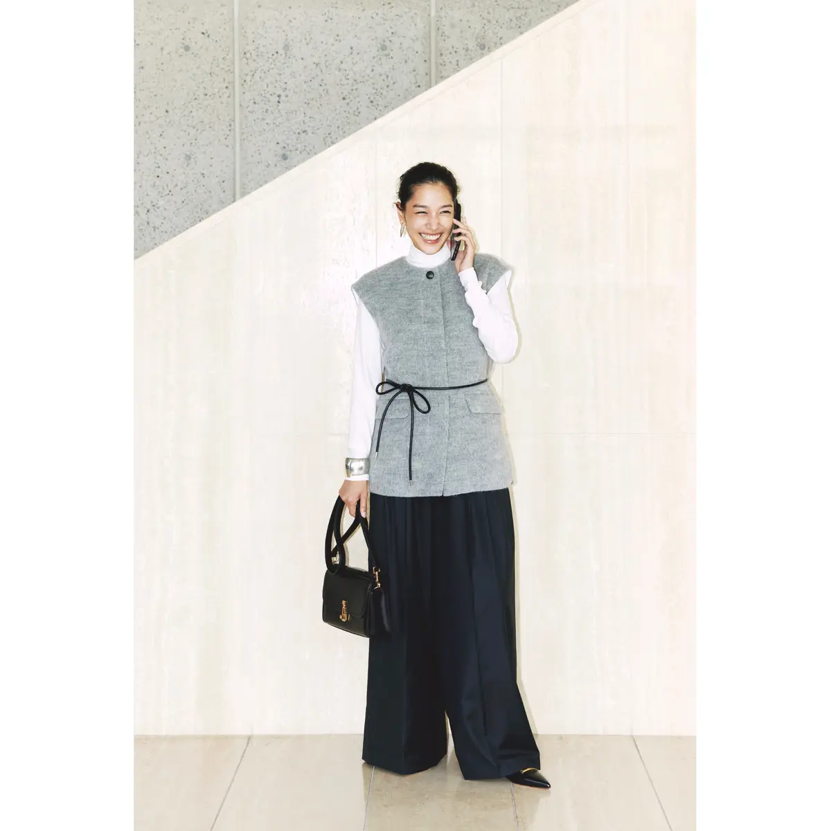 白タートルネックトップスにグレーノーカラージレを重ね、ネイビータックパンツを合わせたコーディネート　モデル・大塚まゆか