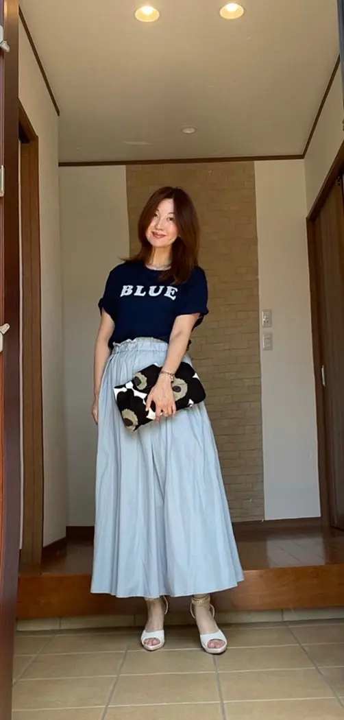 玄関女性　インディゴのTシャツに淡いブルーのマキシスカート