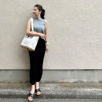 くすみブルーTシャツ、黒のロングニットスカート、黒サンダル、白のエコバッグ