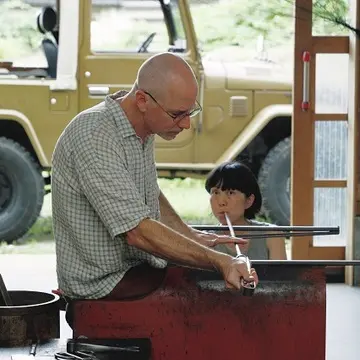 ピーターさんのかけ声で、パートナーのいつかさんが吹き竿に息を吹き入れ、ピーターさんが成型を行う