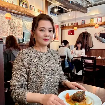 西早稲田の人気ビストロ「フランス食堂 montée（モンテ）」店内でランチを楽しむ女性｜早稲田ランチでおすすめのフレンチ・牛肉の赤ワイン煮込みを味わう様子｜予約必須の隠れ家レストラン
