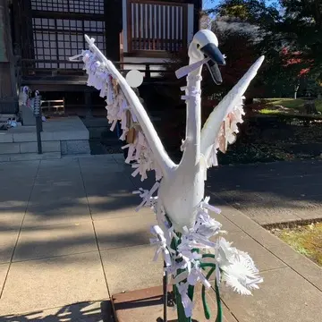 おみくじが沢山結ばれていり白鳥の像