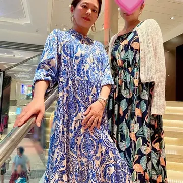 クルーズ船の階段で柄ワンピースを着たポーズをとる二人の女性。