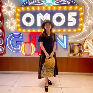 ネオン輝くOMO五反田の前で黒のユニクロワンピースと帽子を合わせたクラシカルな全身コーデ