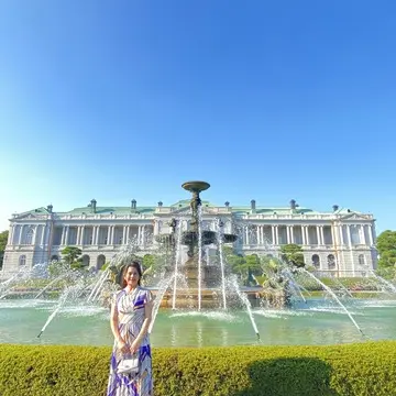 迎賓館の噴水前でポーズをとる女性。ワンピースと背景の建物が美しくマッチしている。