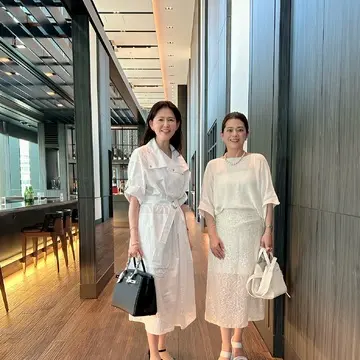 ホテルの廊下で並んで立つ2人の女性。どちらも白を基調とした上品な夏コーデ。