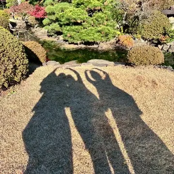 大隈庭園の芝生に伸びる3人の影のシルエット。秋の日差しと紅葉が美しい早稲田大学キャンパス