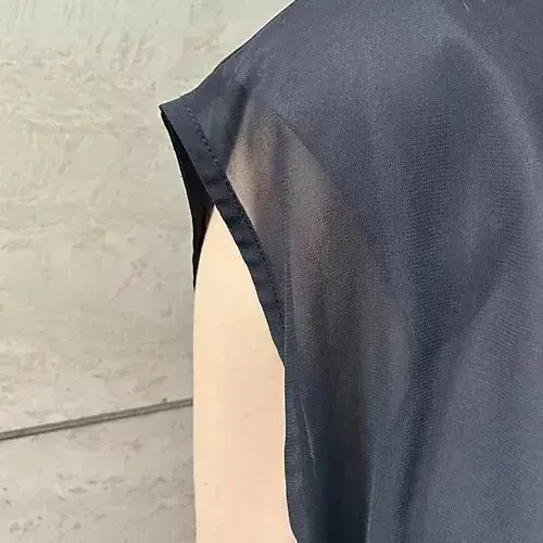 黒いシアー素材の布が左から右に傾斜し、肌色の背景と重なっている
