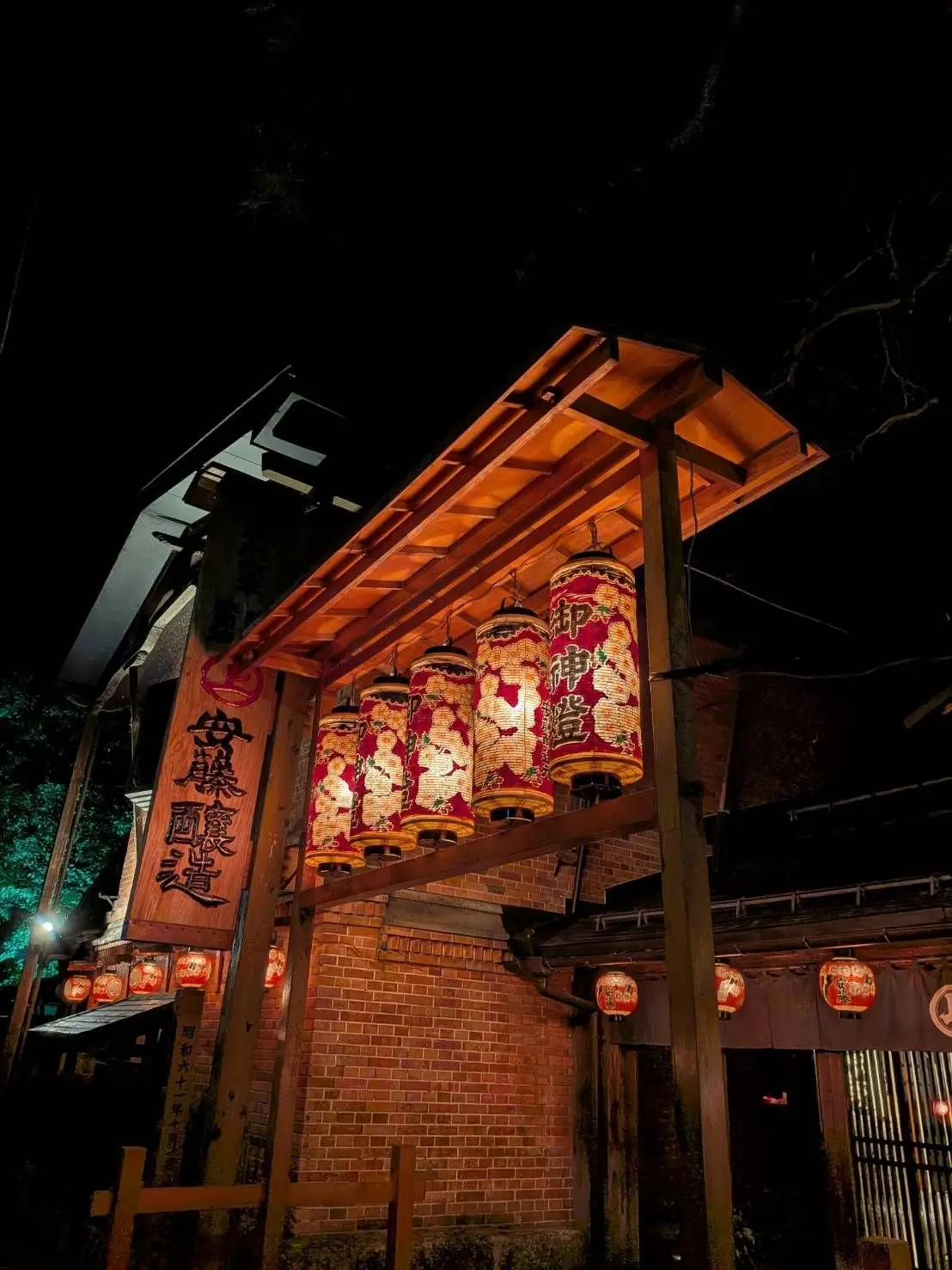 夜の台湾の寺院。赤と白の提灯が並び、木造の建物がライトアップされている。看板には中国語の文字が書かれている。