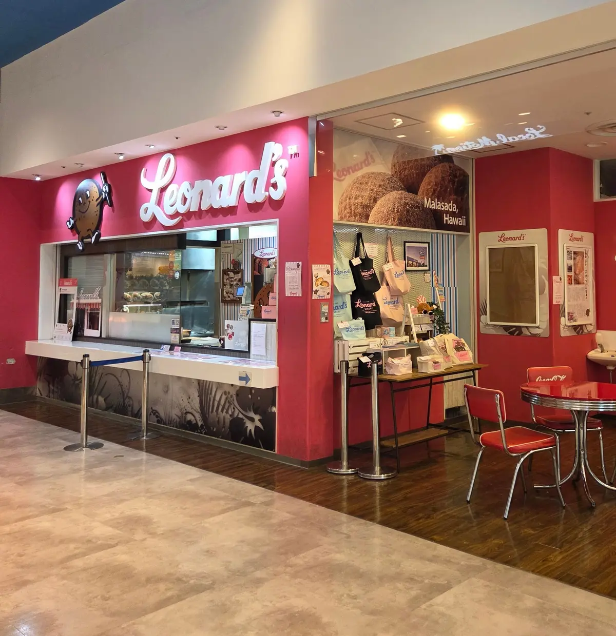 フードコート内の「Leonard's」の店舗。赤色の外観で、ショーケースには様々なお菓子が並び、テーブルと椅子が設置されている。背景には青色の天井が見える。
