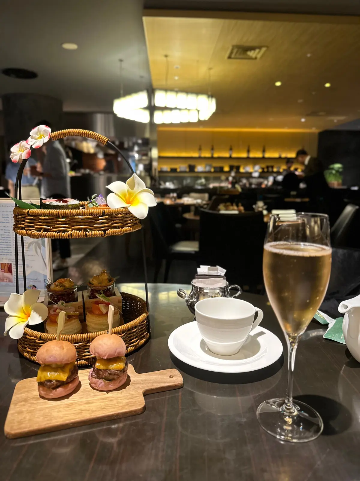 ワゴンの上に花飾りが付いた軽食と、グラスに注がれたシャンパン、テーブルに置かれたコーヒーカップが並ぶレストランの内装