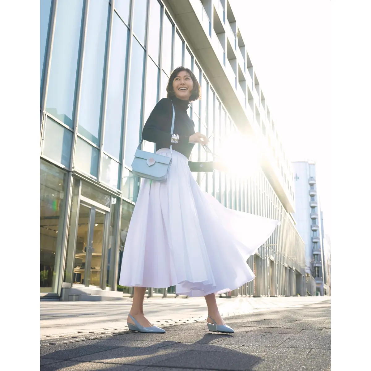 黒タートルトップスに白フレアースカートを合わせ、バッグとパンプスで爽やかな水色を効かせたたコーディネート　モデル・田丸麻紀
