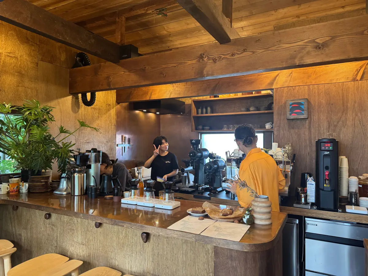 木製のインテリアの店内、カウンターにはコーヒー機やカップが並び、スタッフがコーヒーを提供している