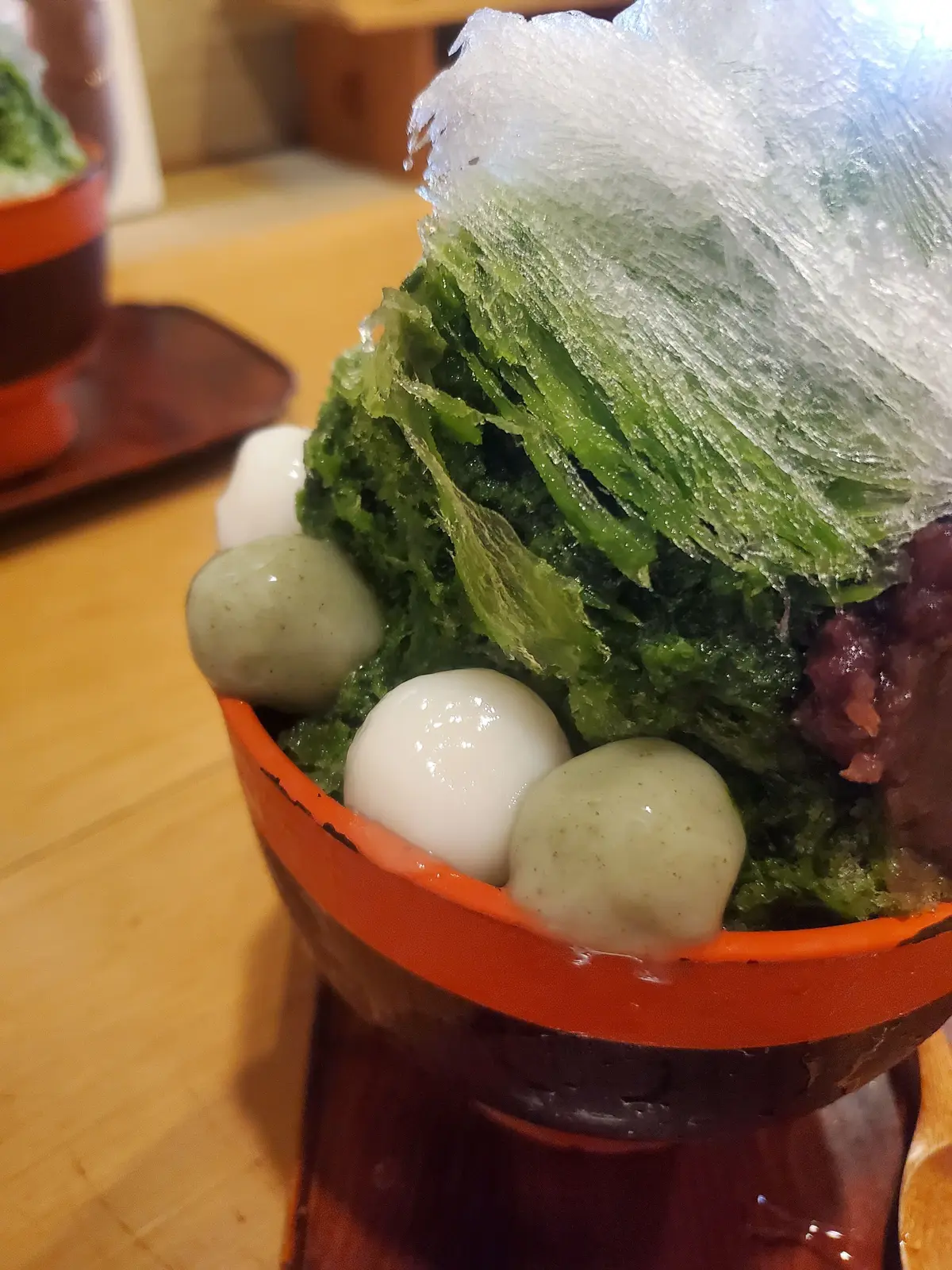 茶色い器に盛り付けられた、紫色の煮物、緑色の海苔、白玉、綿あめのような白い菓子が付いた和食。