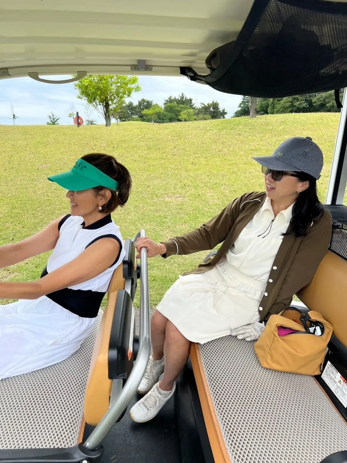 ゴルフカートに座る桶田直子さん、松井陽子さん