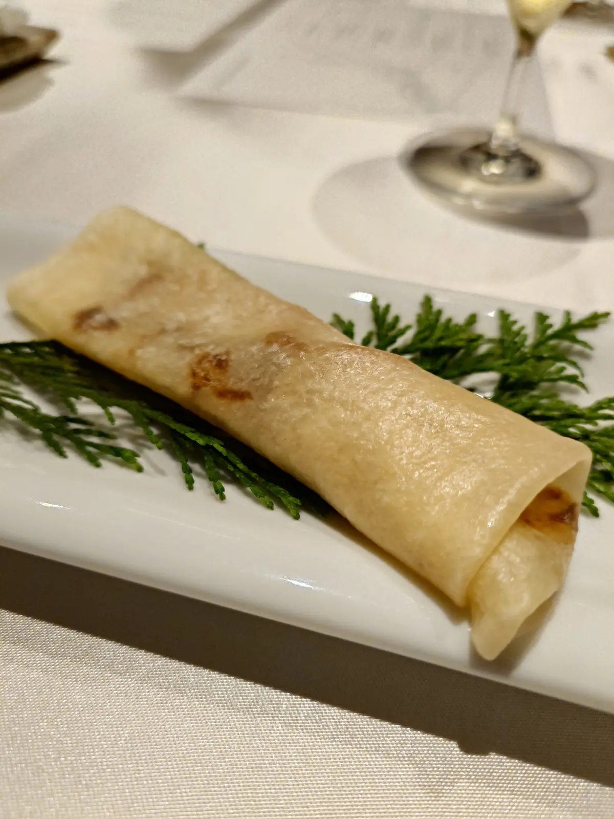 白いプレートに、茶色い焦げ目が付いた巻き物と緑のシダの葉が並んでいる