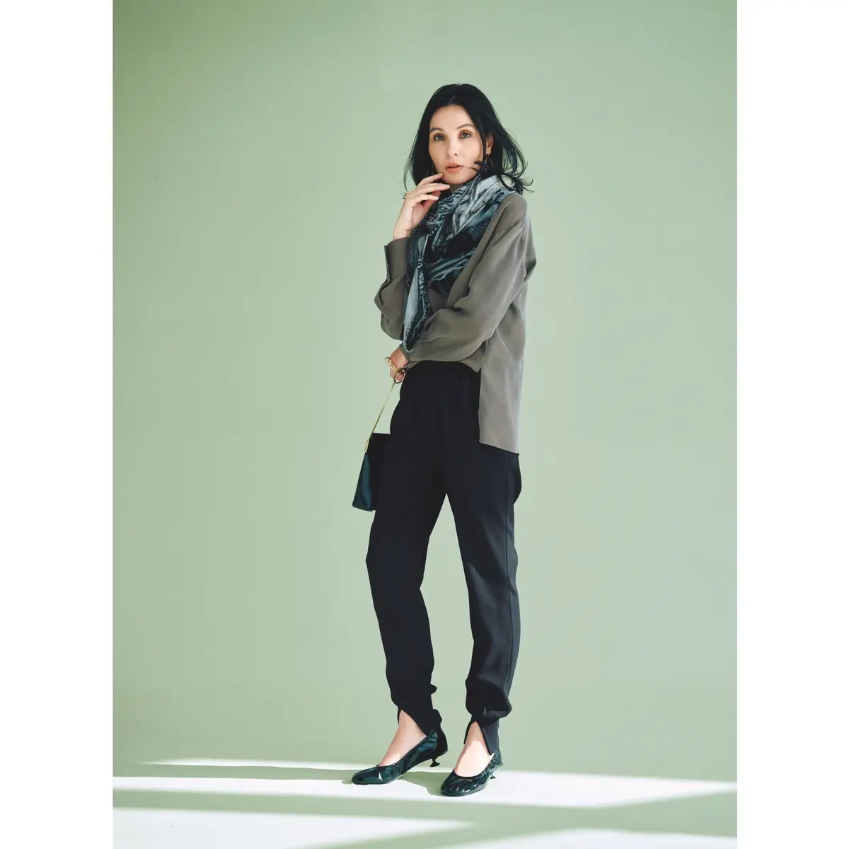 グレーブラウスと黒ジョガーパンツに、首元はブルーのプリントストールを巻き、足元は黒パンプスを合わせたコーディネート　モデル・田沢美亜
