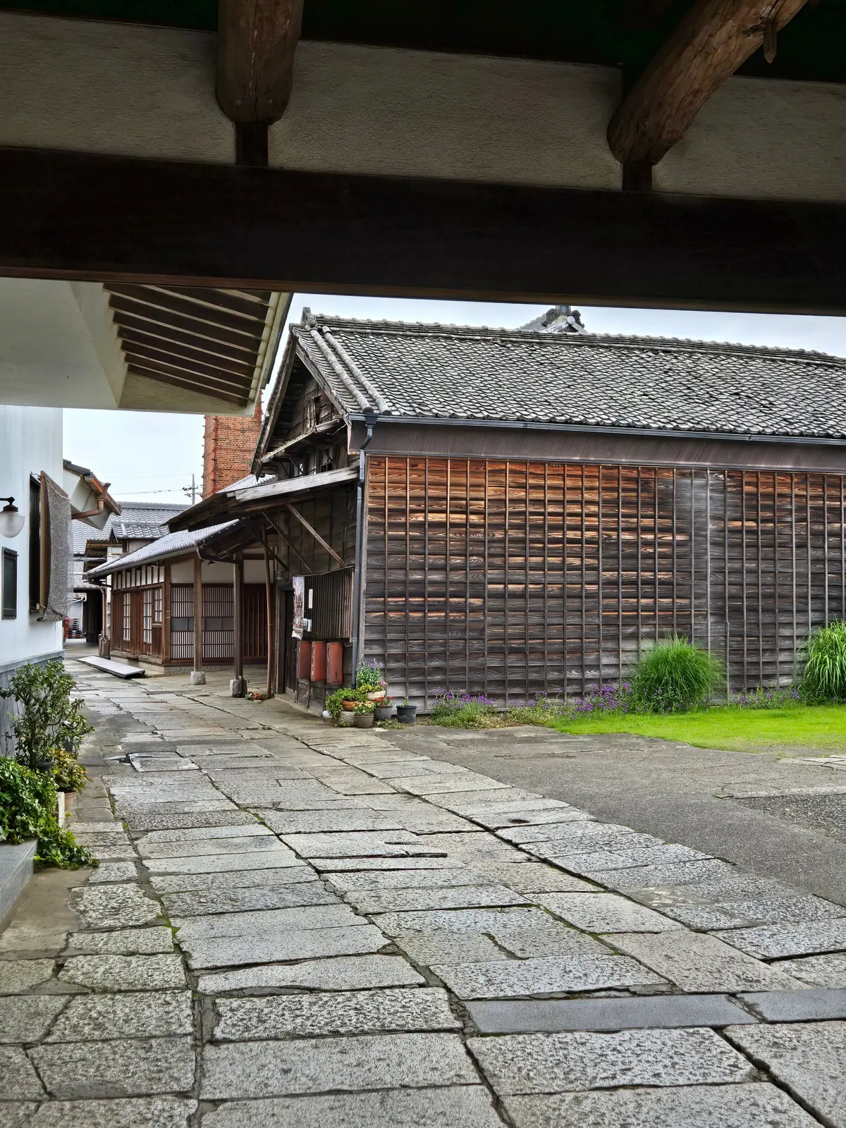 石畳の道が伝統的な木造建築の通りを通り、木製の格子と瓦屋根の家が並ぶ歴史的な町並み