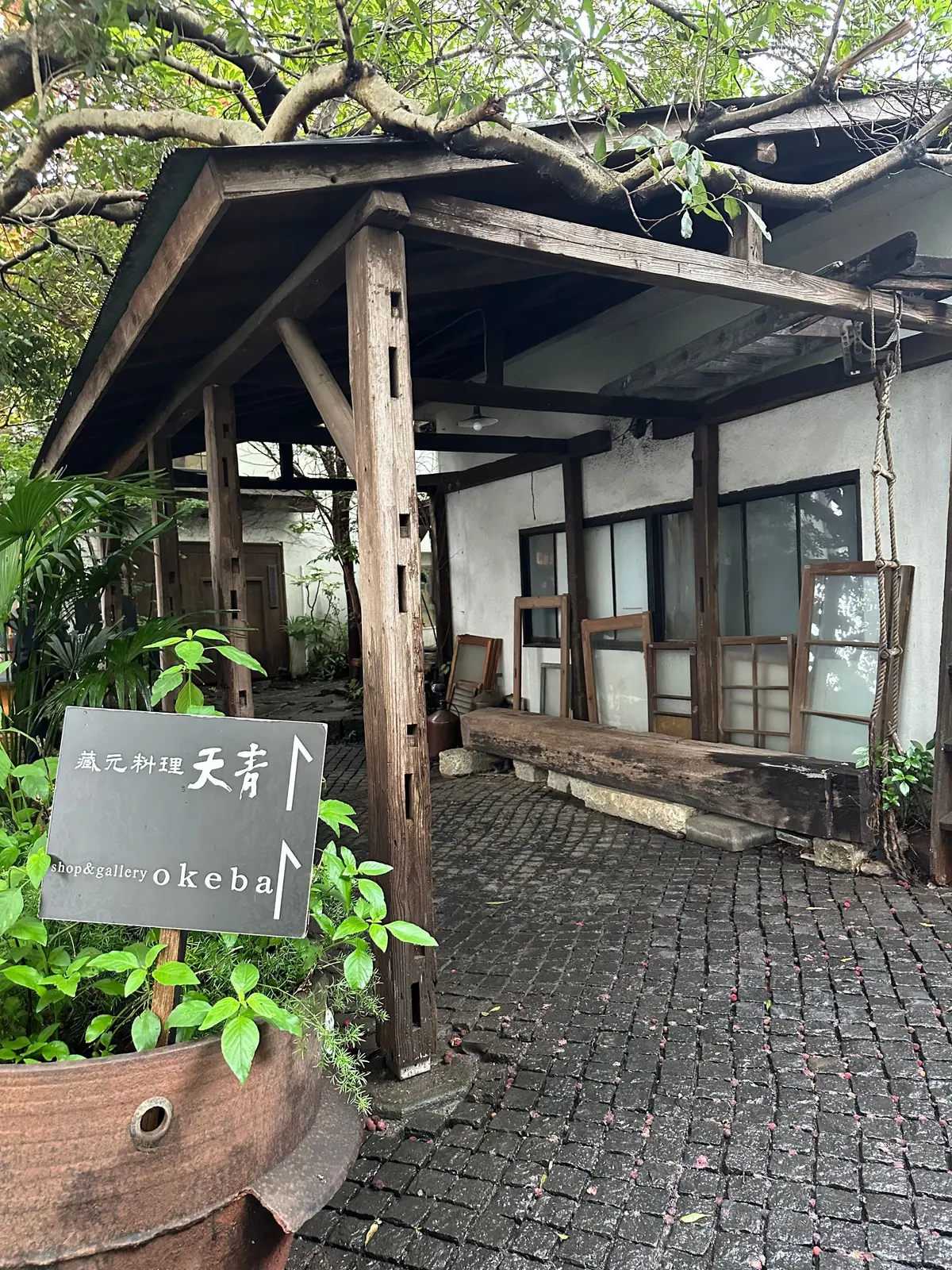 木造の店先、木の柱と屋根付きのテラス、石畳の通路、店名表示板「店元料子屋上」の文字が書かれている