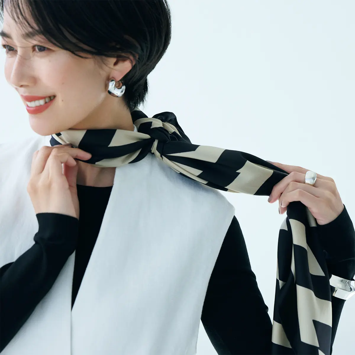 そのまま首後ろへ結び目を回 し、首前の柄の出方を整える