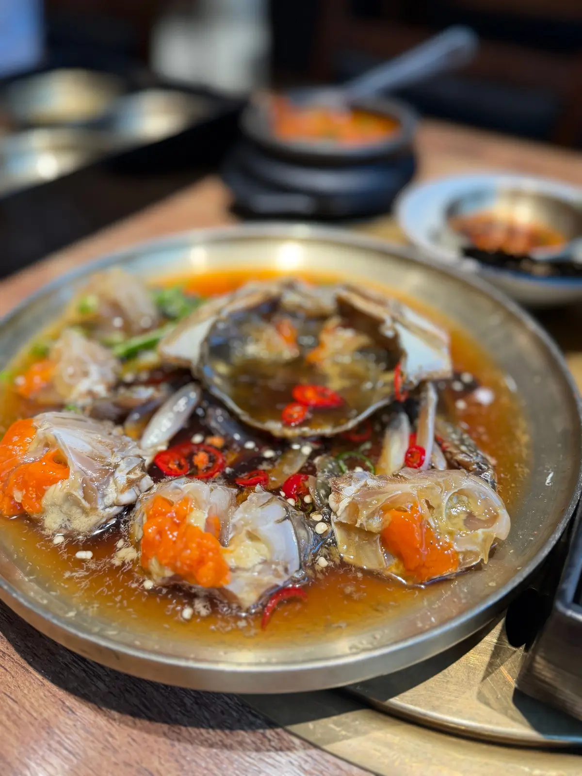 魚の煮込み料理が銀の皿に盛り付けられ、赤唐辛子と野菜が添えられています。