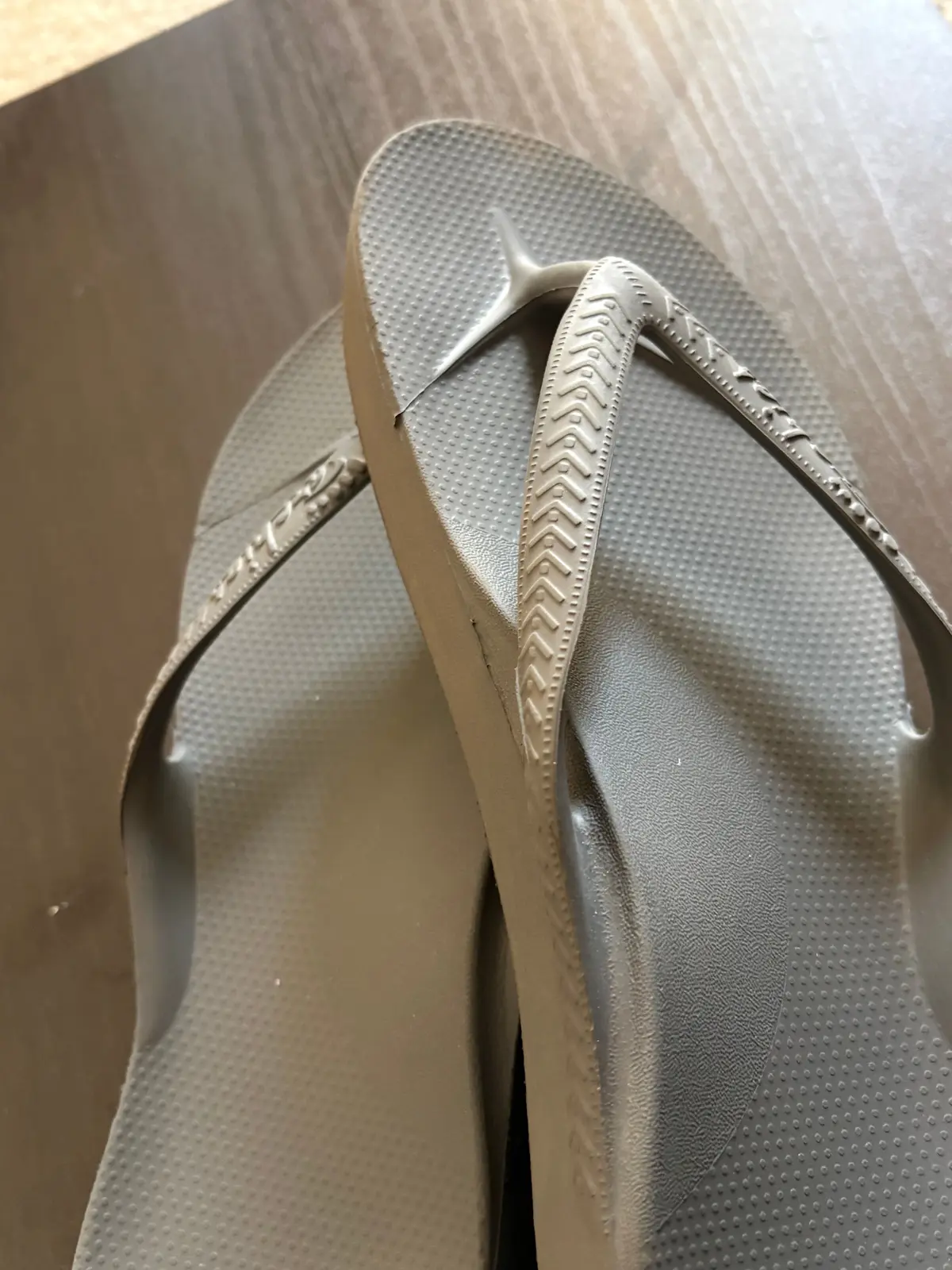 灰色のビーチサンダルが二つ並んでいる。足の形に沿ったフットベッドで、Nikeのロゴが刻印されている。
