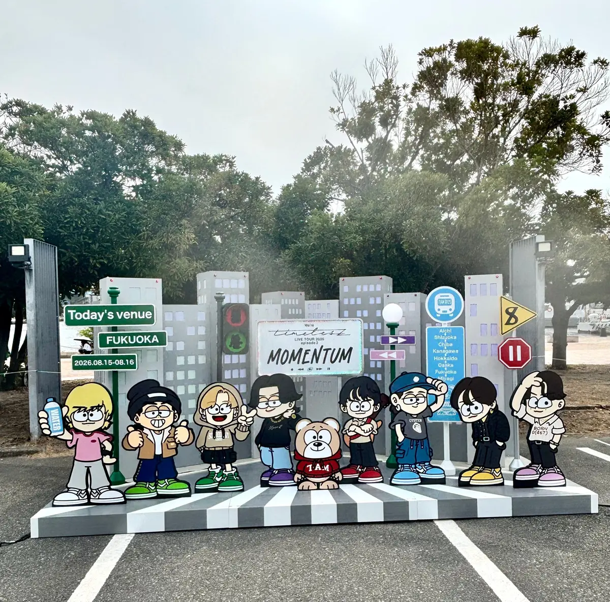 福岡の街並みを背景に、人気グループTOMORROW X TOGETHER（TXT）のメンバーをモチーフにしたイラストが、横断歩道の上に設置されている。