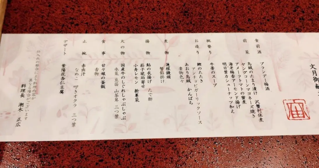 赤い花模様の紙に日本語で記載されたメニュー、右下に赤い印あり
