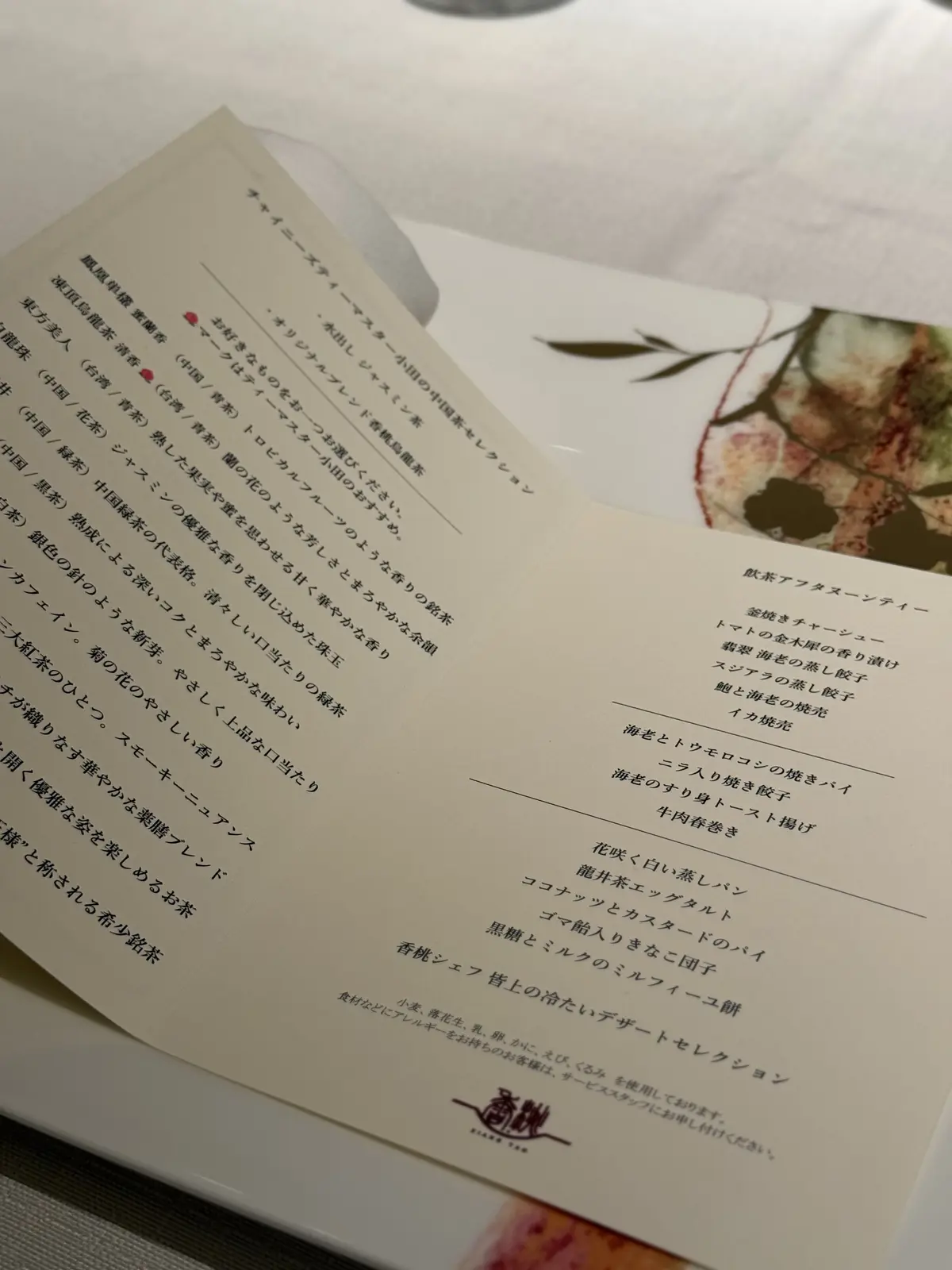 日本のレストランのメニュー。左ページは料理の説明が日本語で記載されており、右ページは魚介料理を中心とした献立が日本語と英語で記載されている。メニュー全体は白地に黒い文字で印刷され、写真も掲載されている。下部に「SUISA」のロゴマークがある。