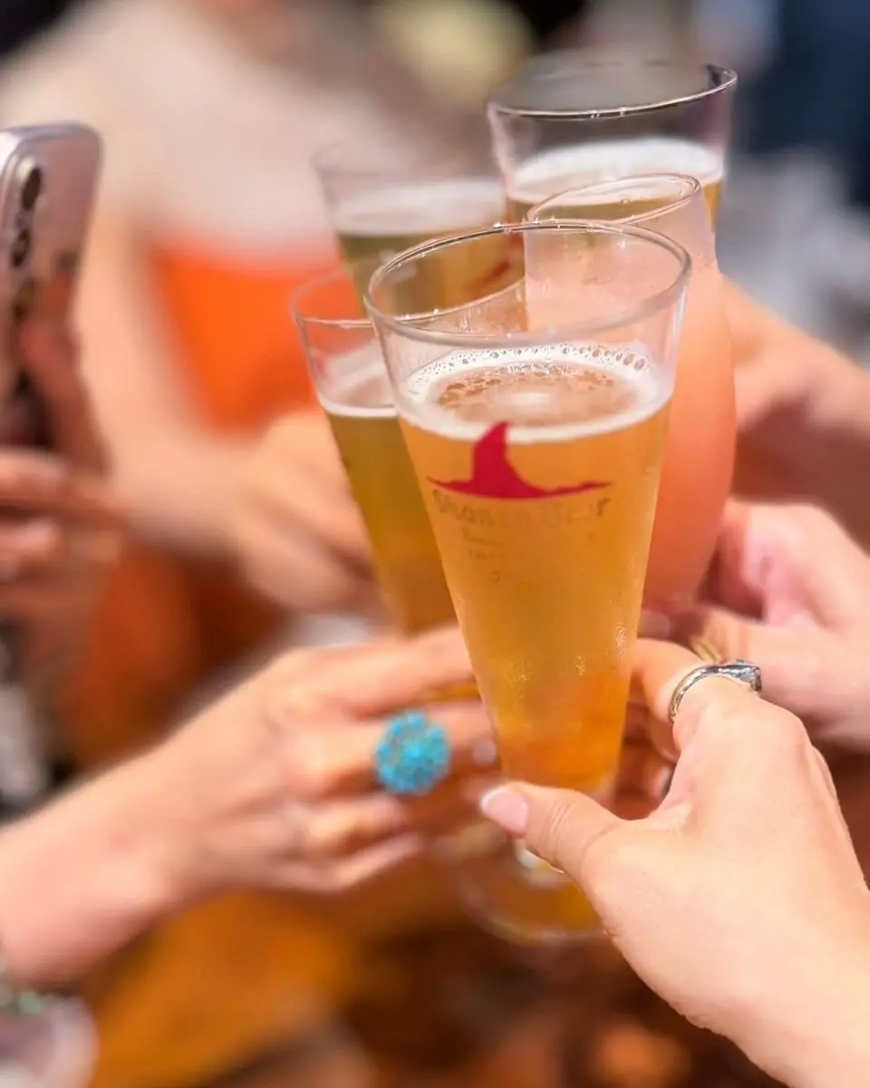 複数のグラスが並び、人々が楽しそうに乾杯している様子。中央のグラスには「Shoen Beer」のロゴが入っている。