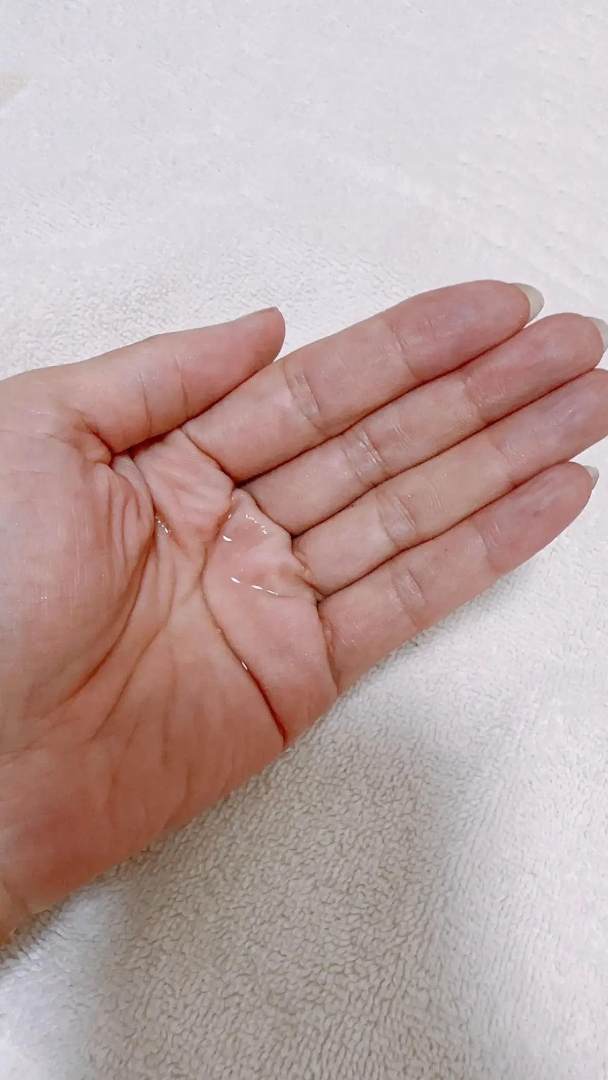 白いタオルを敷いた手のひらに、透明なジェル状の液体が置かれている様子。