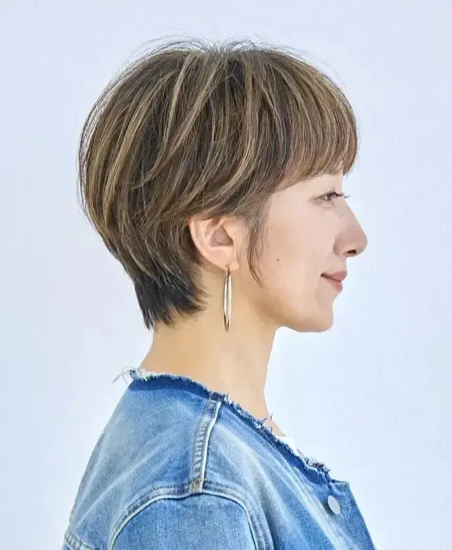 ブラウンのショートヘアの女性で、耳飾りを身につけ、デニムジャケットを着ている
