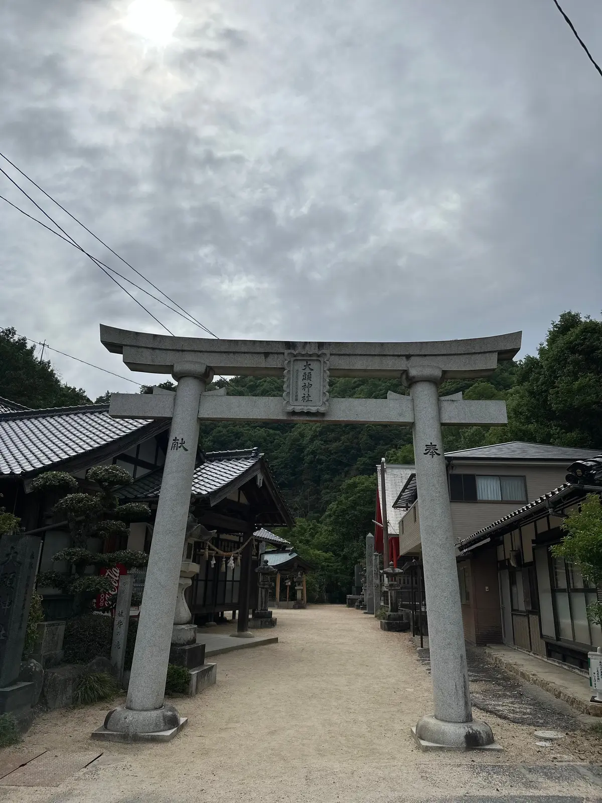 石造りの鳥居が道を挟んで立ち、両側に伝統的な神社や家屋が並ぶ道