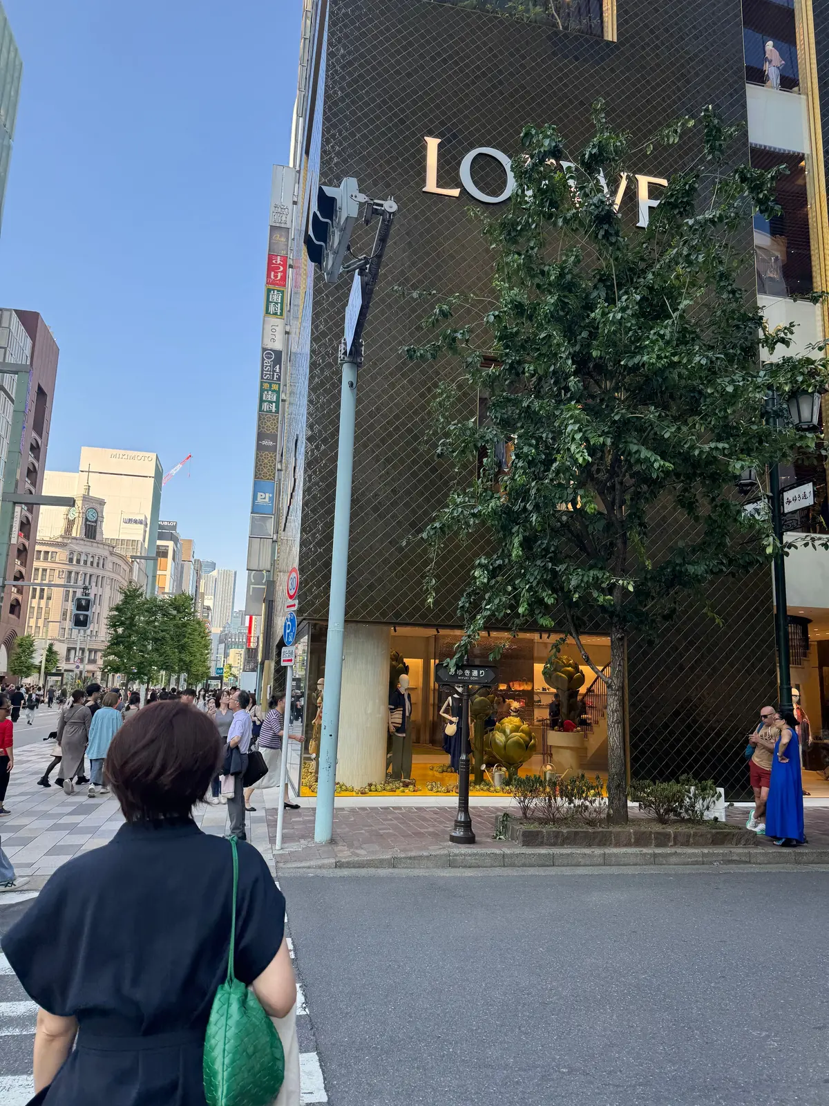 ロレックスの店頭に人々が歩く都市通り、店内には展示品が並ぶ